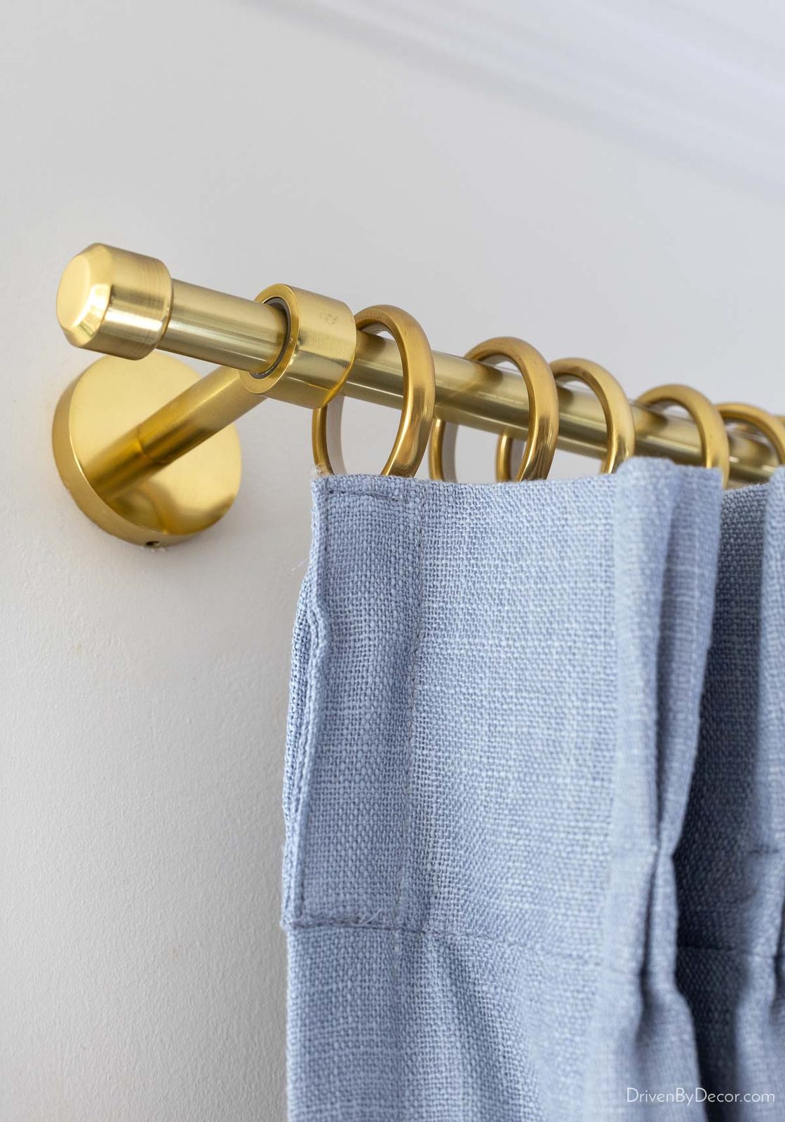 Aged brass curtain rod with dusty blue curtains