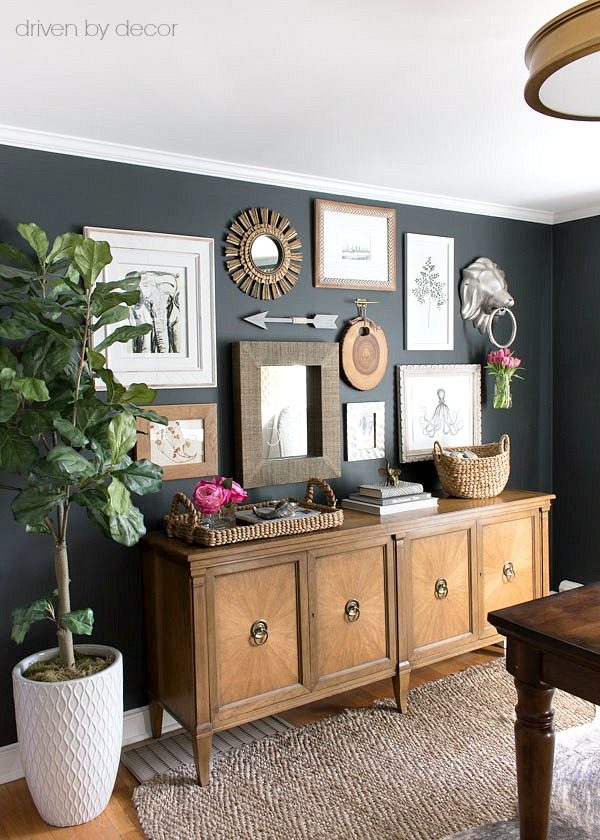 Great gallery wall arrangement with art prints and mirrors above a vintage console