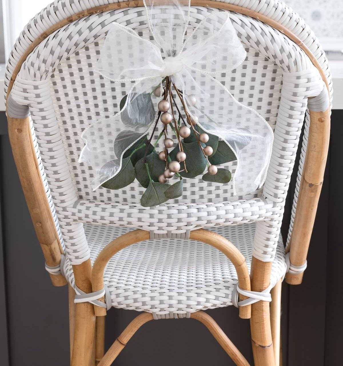 Mini greenery swags tied with a bow are the perfect simple Christmas decorations for the backs of our chairs