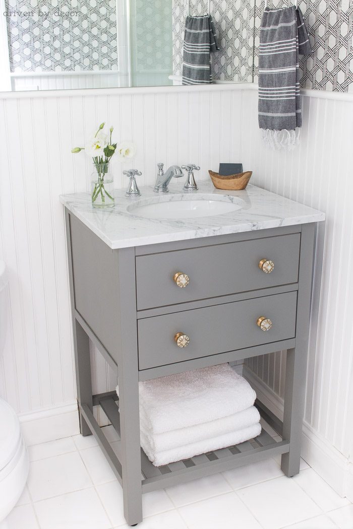 Small space single sink gray vanity with white marble top and classic Delta Cassidy bathroom faucet - links to everything in post!