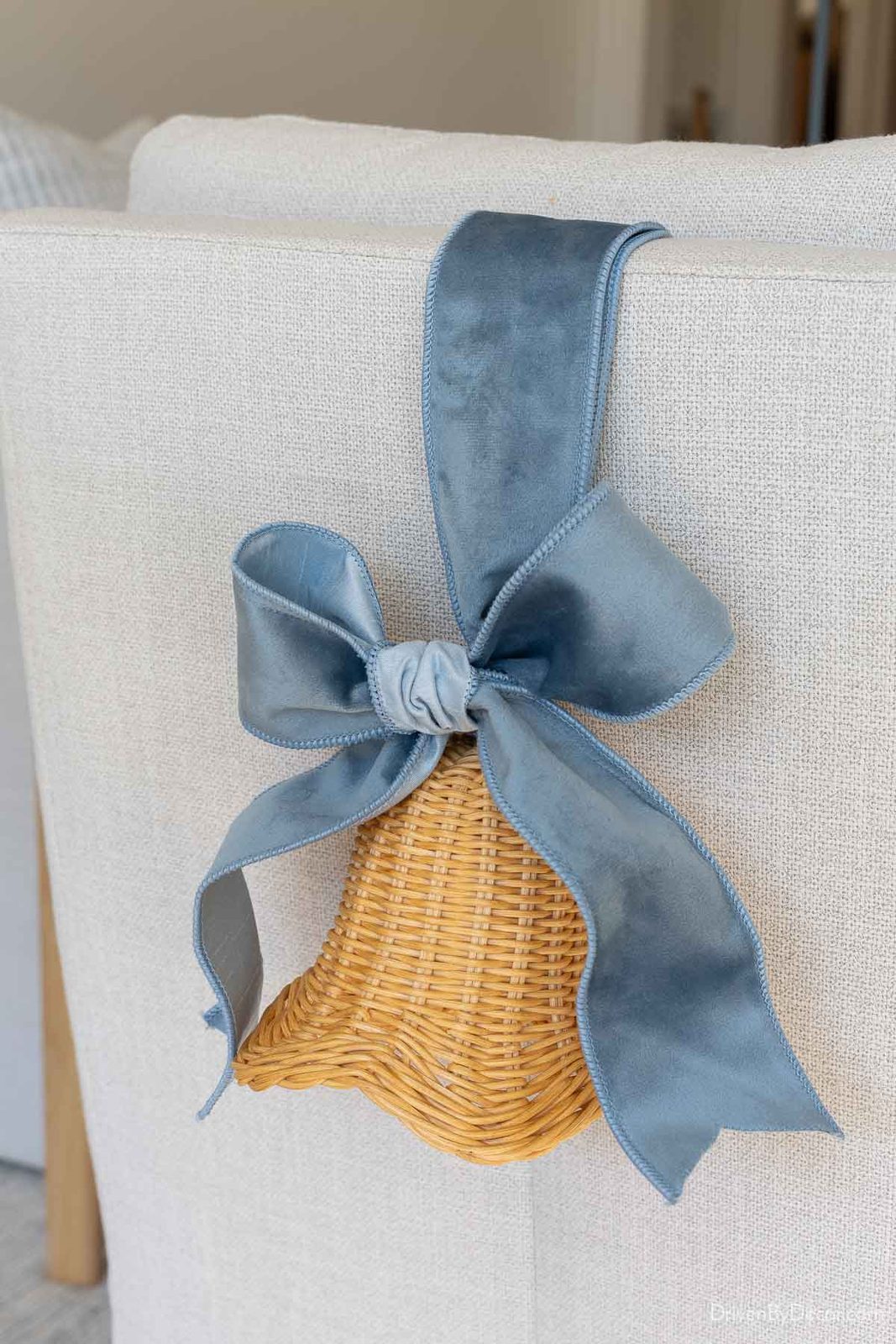 Rattan bells with velvet ribbon on back of chair for coastal Christmas decor