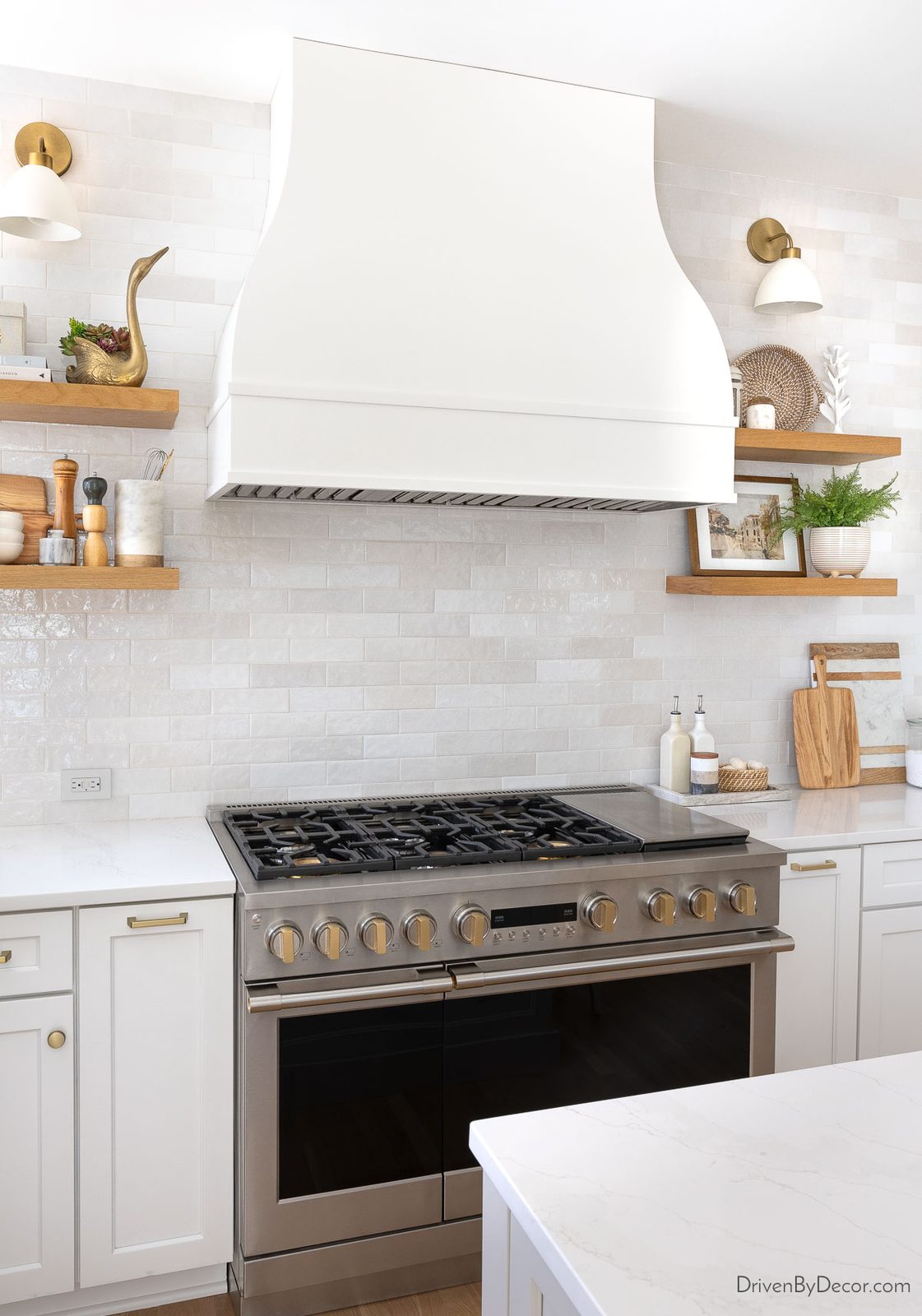 Kitchen range and bell shaped hood with floating wood shelves and sconces