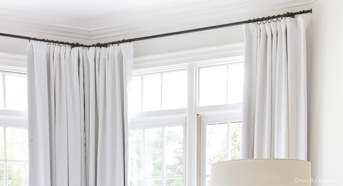Corner curtain rod holding white curtains