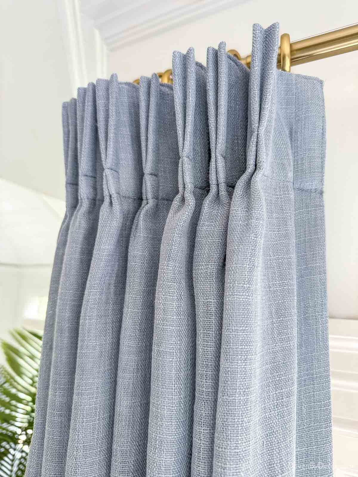 Pleated dusty blue curtains in bay window
