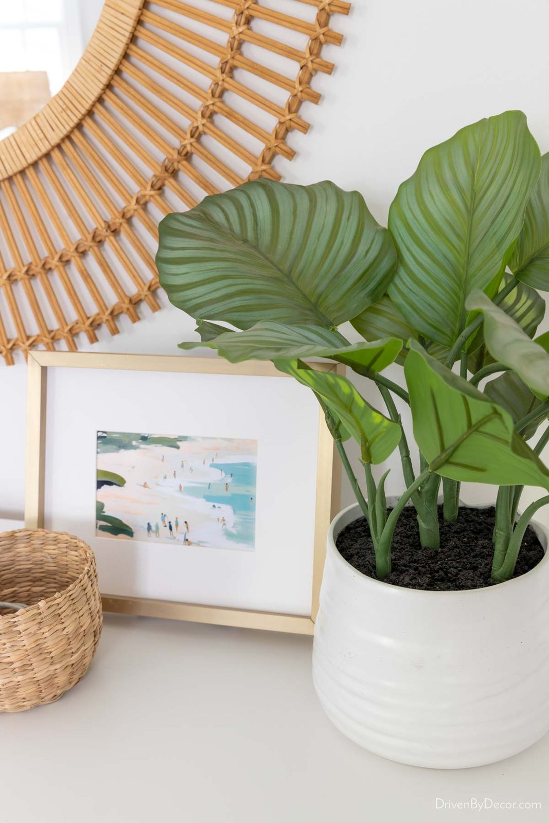 Faux green plant with large leaves on bedroom dresser