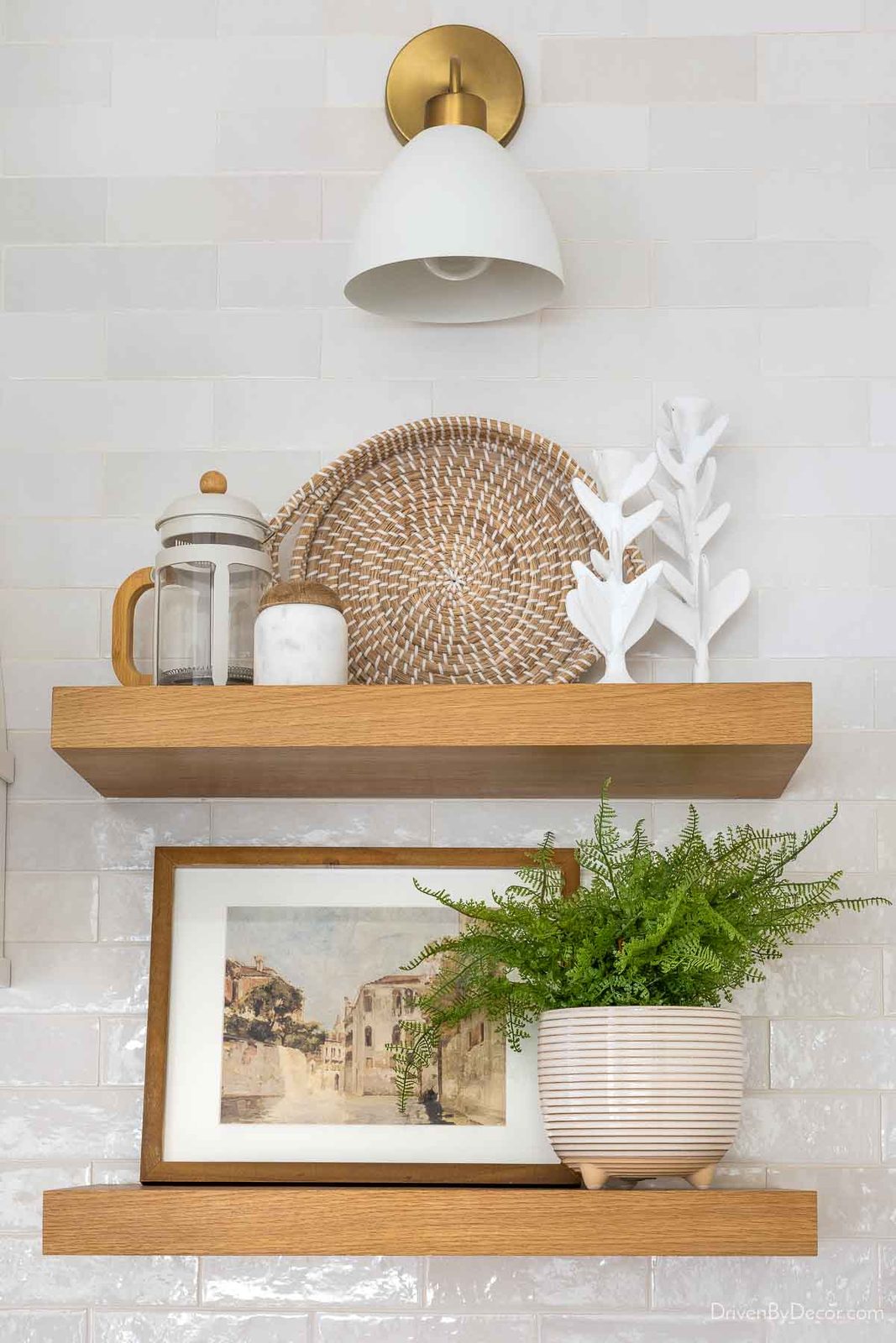 Framed art print and other accessories on floating shelves in kitchen
