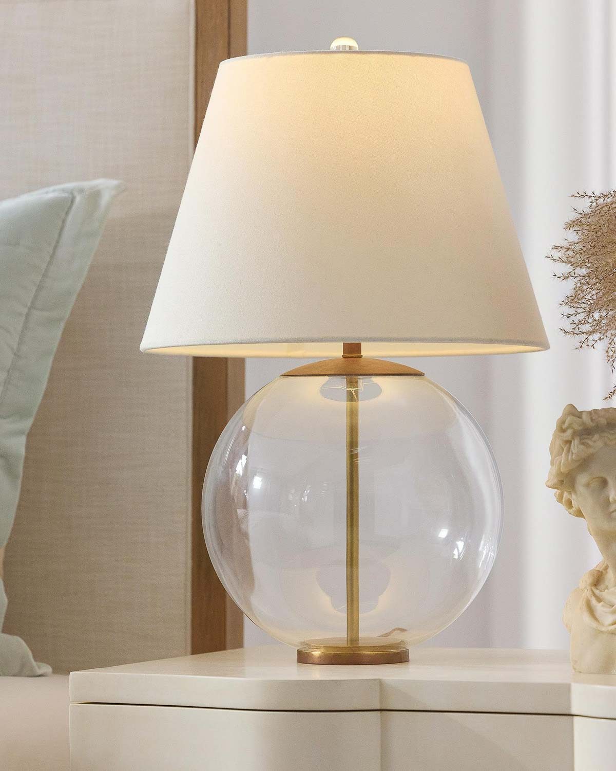 Glass orb lamp with brass details on nightstand