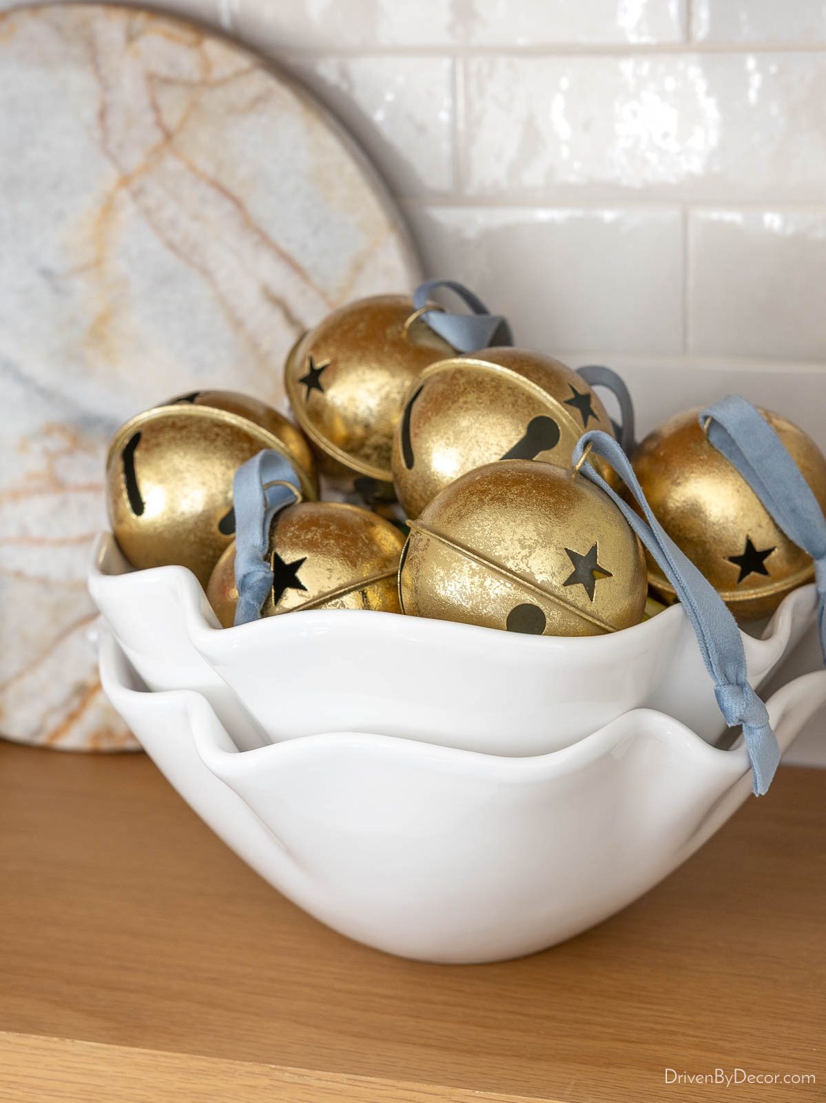 Scalloped white bowls filled with large gold jingle bells