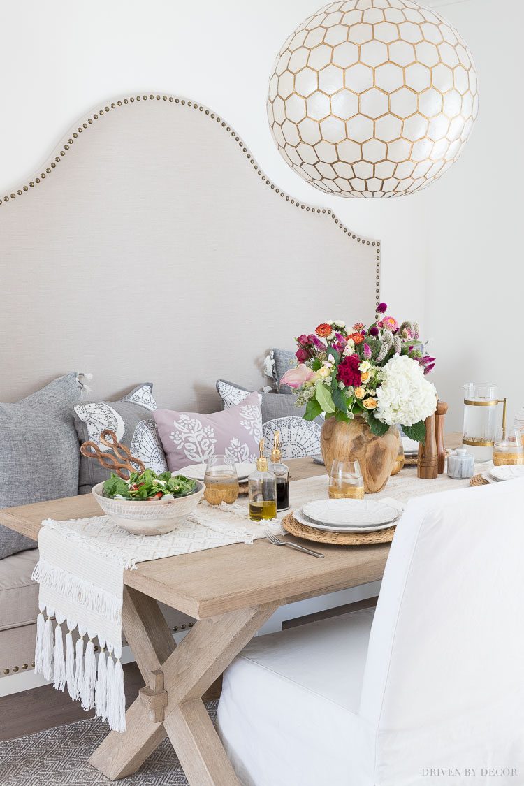 Our kitchen eat-in area with a built in banquette, trestle table, and capiz pendant lighting