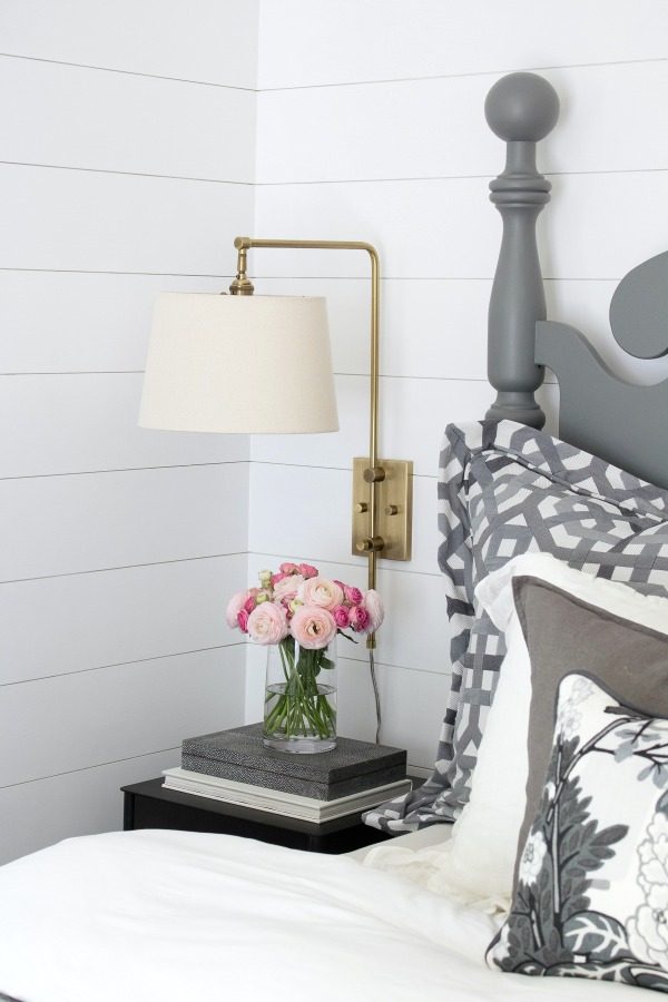 Brass swing arm sconce mounted above nightstands