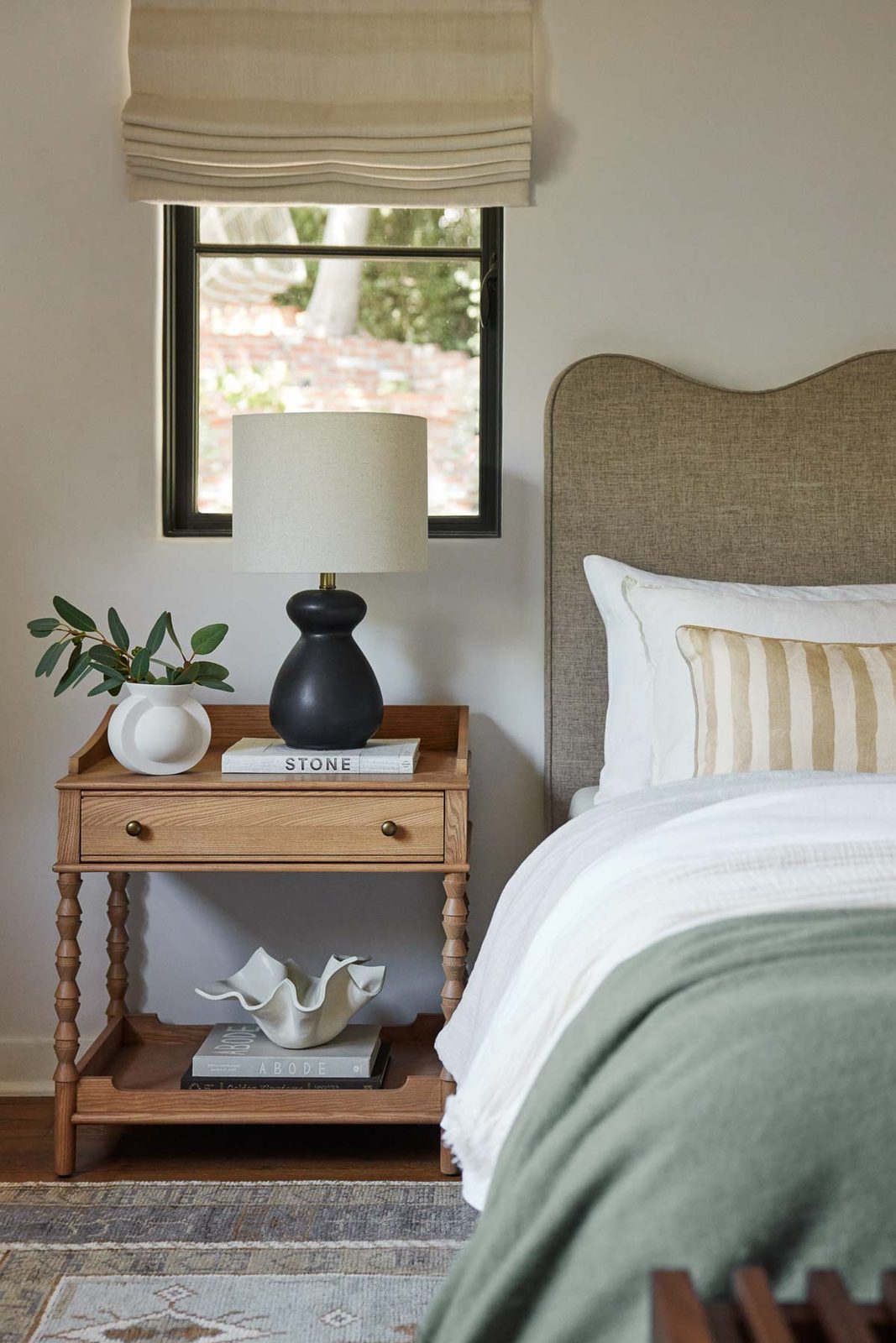 Beautifully styled nightstand with light, greenery, and book