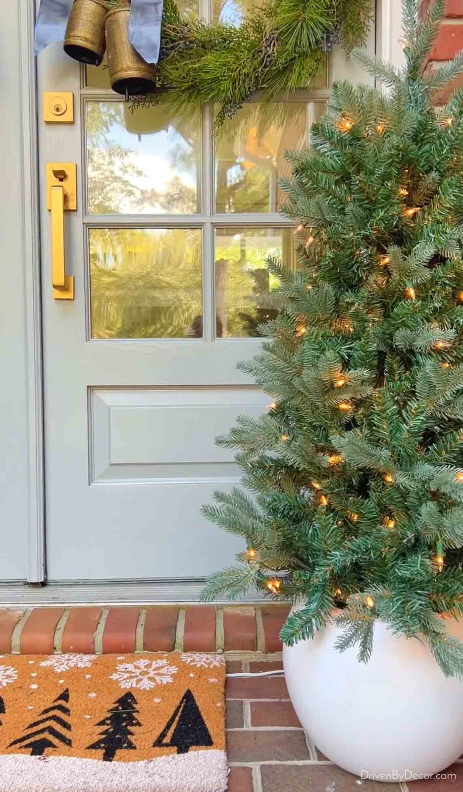 Lighted mini Christmas tree in round white pot on front porch