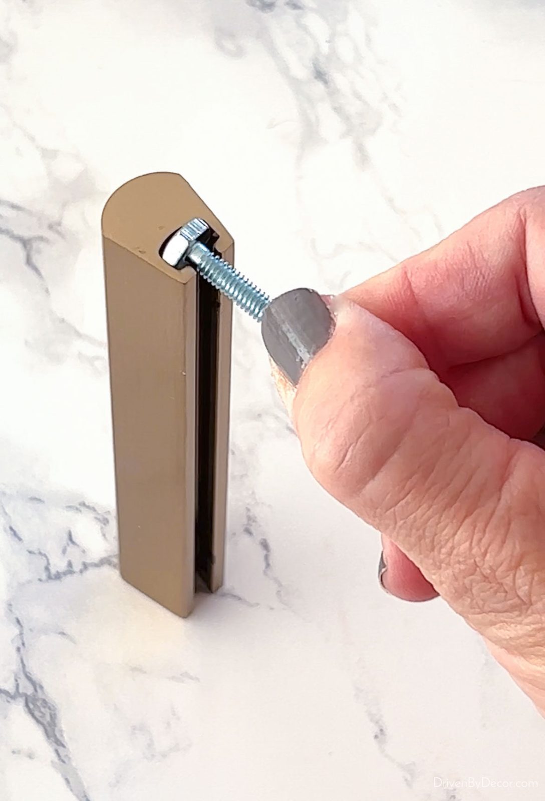 Screw head that fits in opening of adjustable cabinet pull
