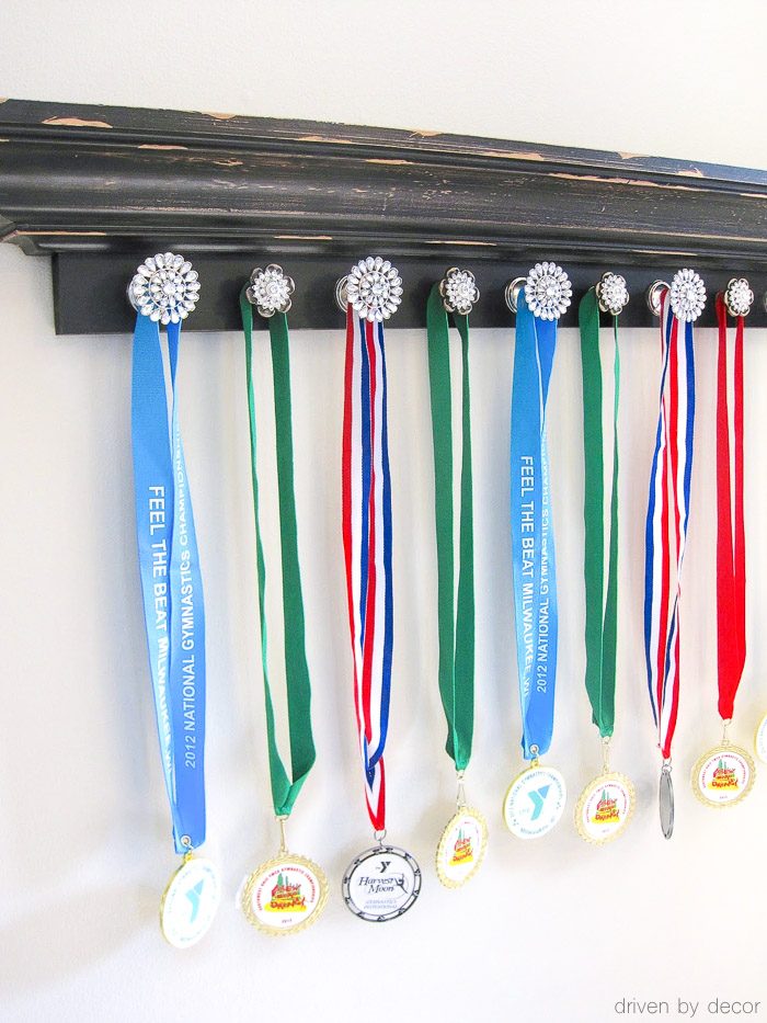 Ledge shelf with knobs attached to hold sports medals - love this idea!