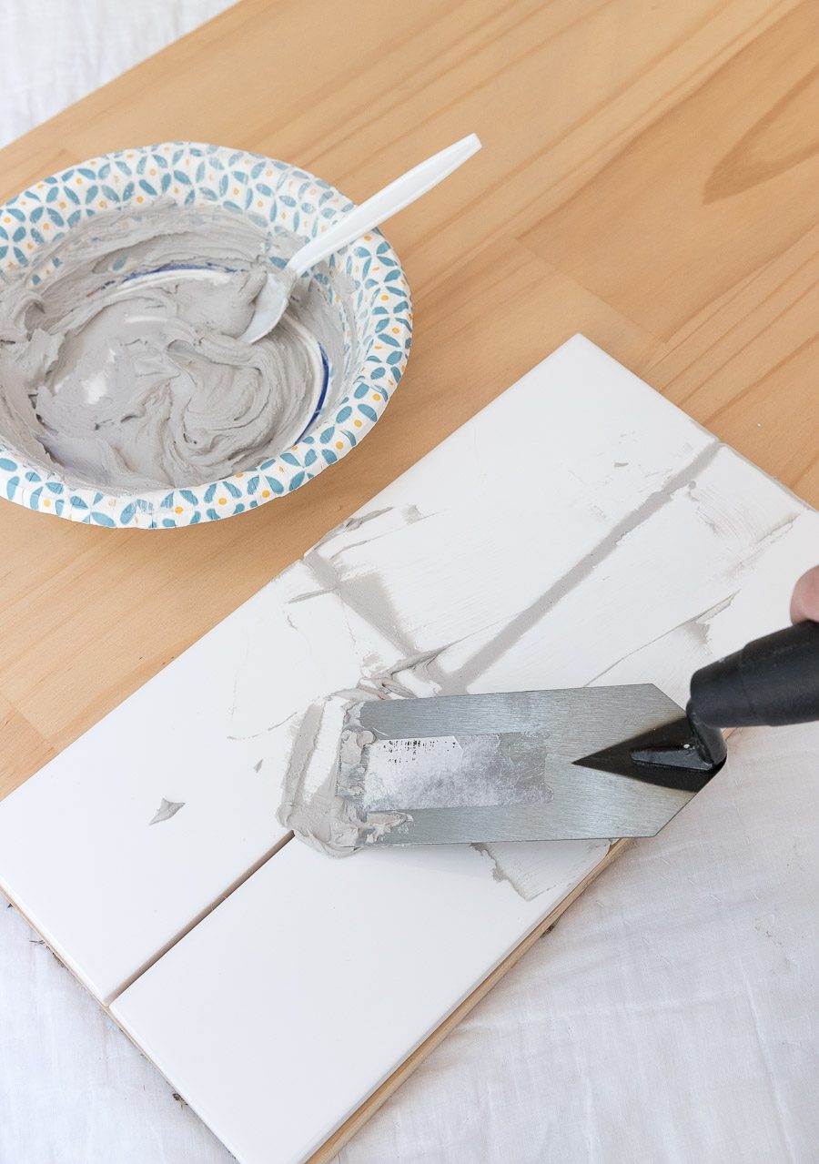 Applying grout to grout sample tiles - I great way to choose the best gray grout for your white subway tile!