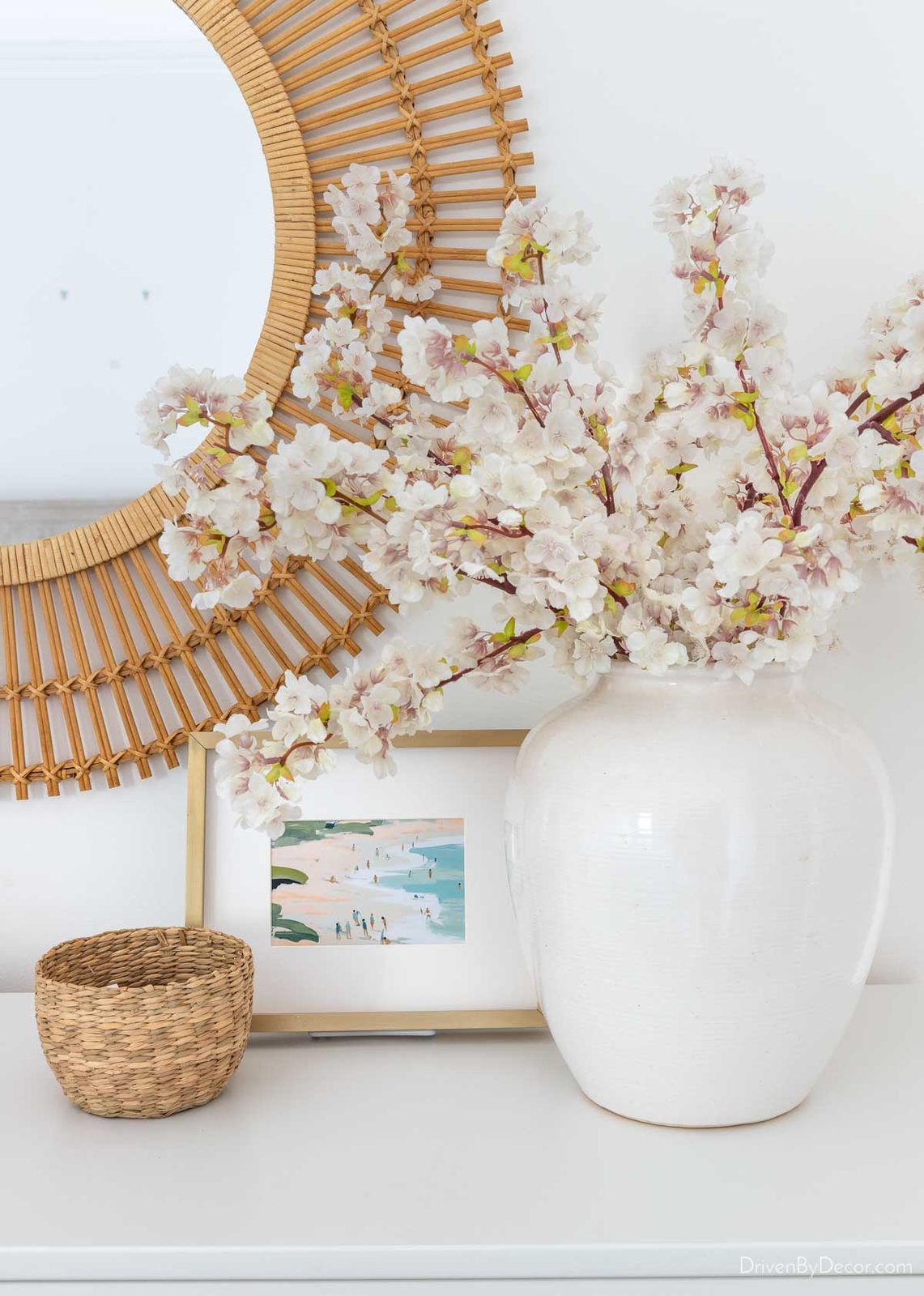 Faux cherry blossoms in white vase on dresser
