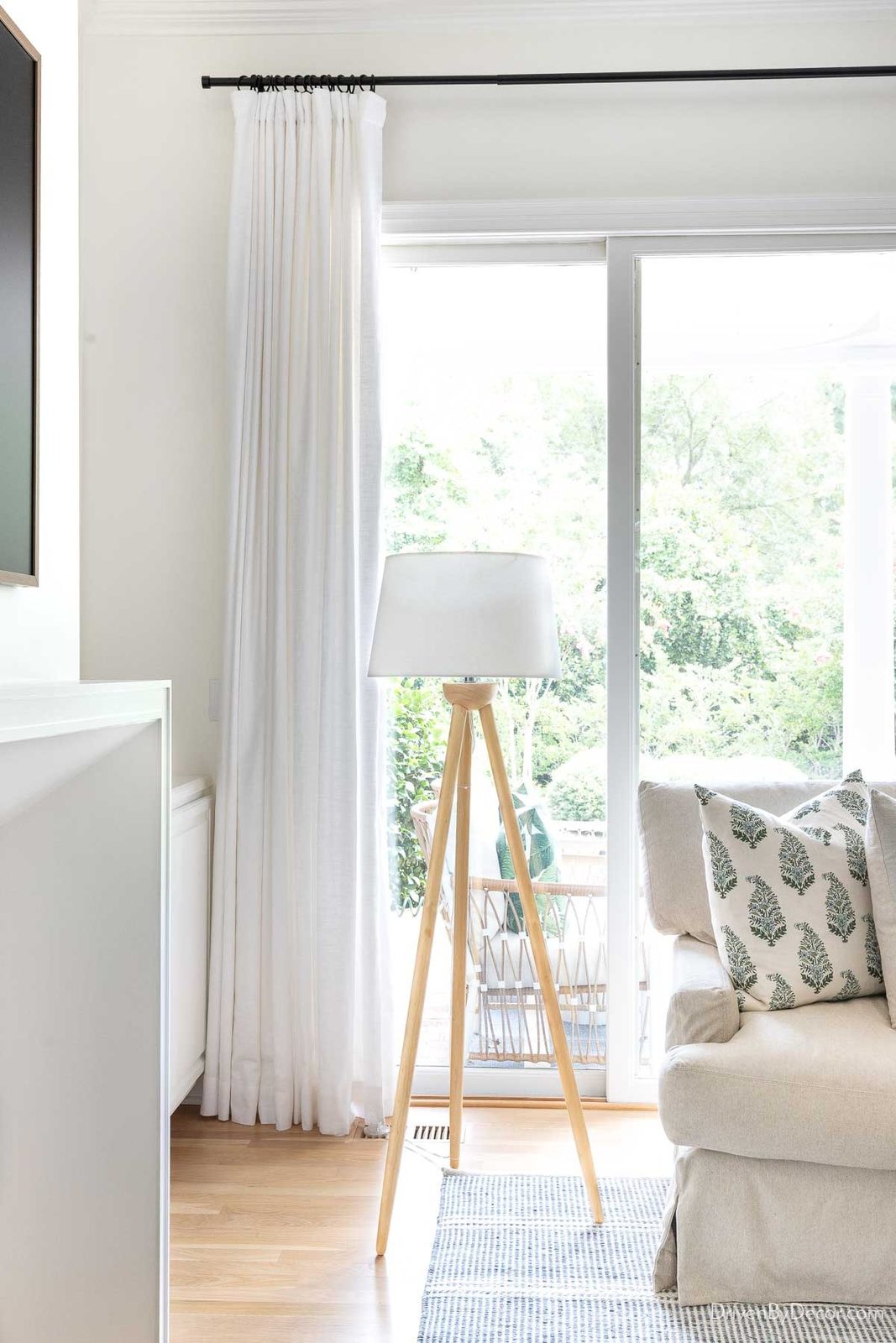 Wood tripod lamp next to sectional in family room