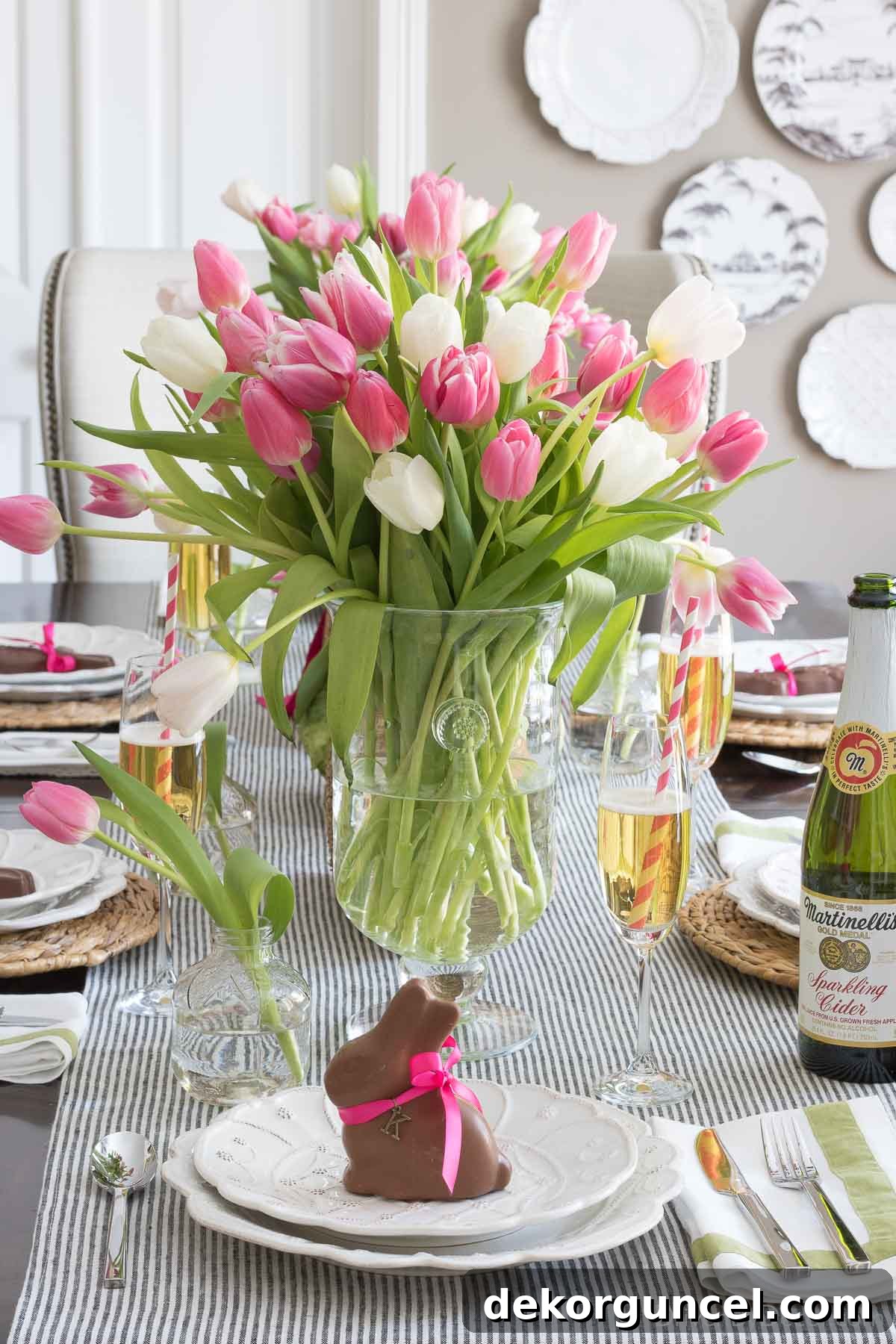Easter place setting featuring a chocolate bunny acting as a place card on a plate, with a vase full of fresh tulips as a centerpiece.