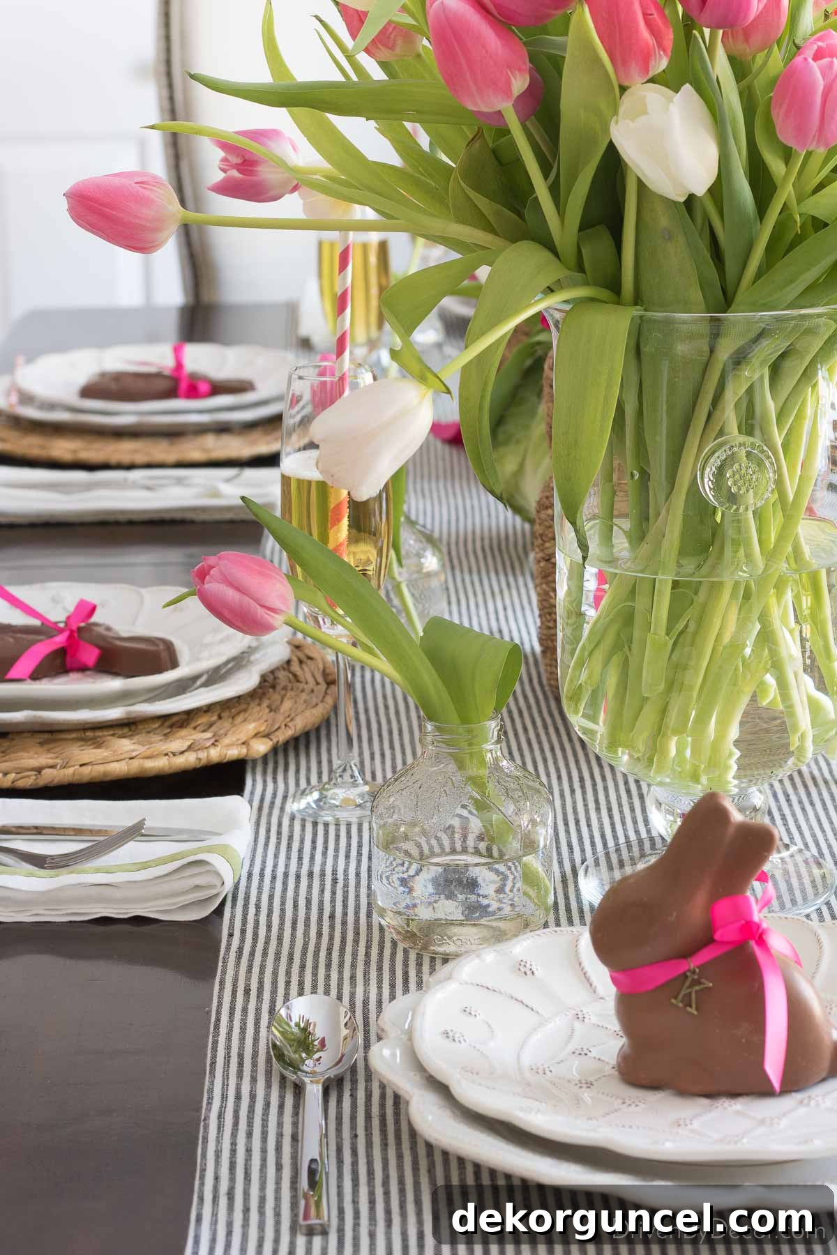 A mini vase filled with a single vibrant tulip, elegantly positioned at the top of an individual Easter place setting, adding a delicate floral touch.