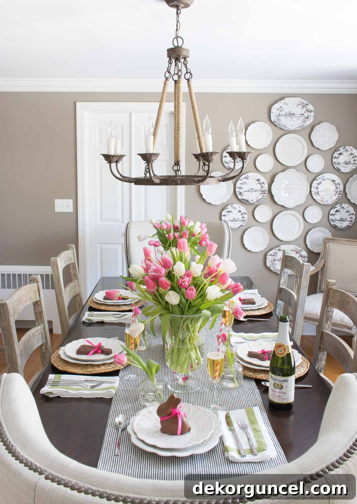 Close-up of a beautifully decorated dining table for Easter, showcasing fresh tulips in glass vases and whimsical chocolate bunnies nestled among the place settings, radiating festive charm.