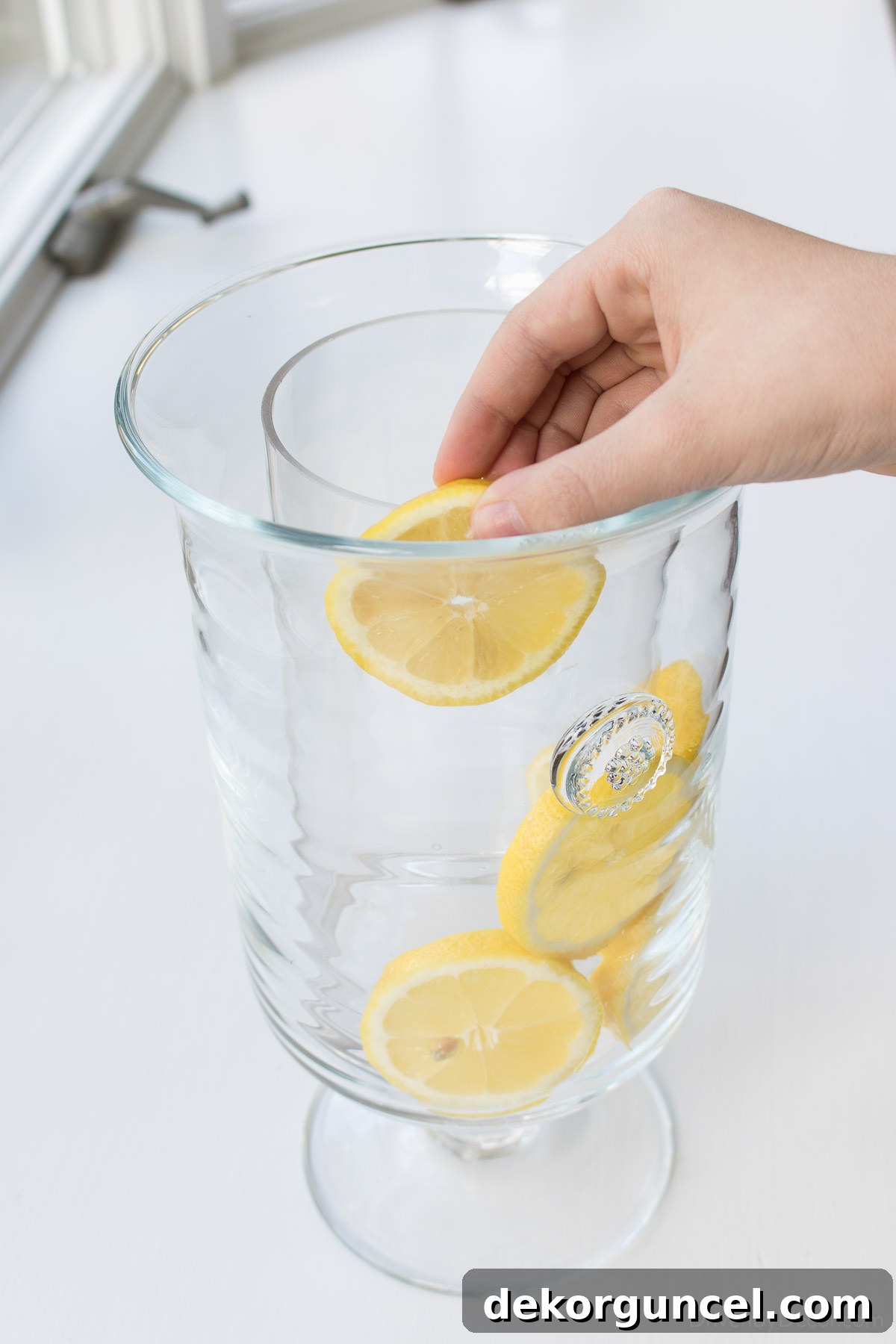 Detailed view of adding lemon slices in the space between two nested vases, creating a beautiful and unique lemon-lined floral arrangement for a fresh spring look.