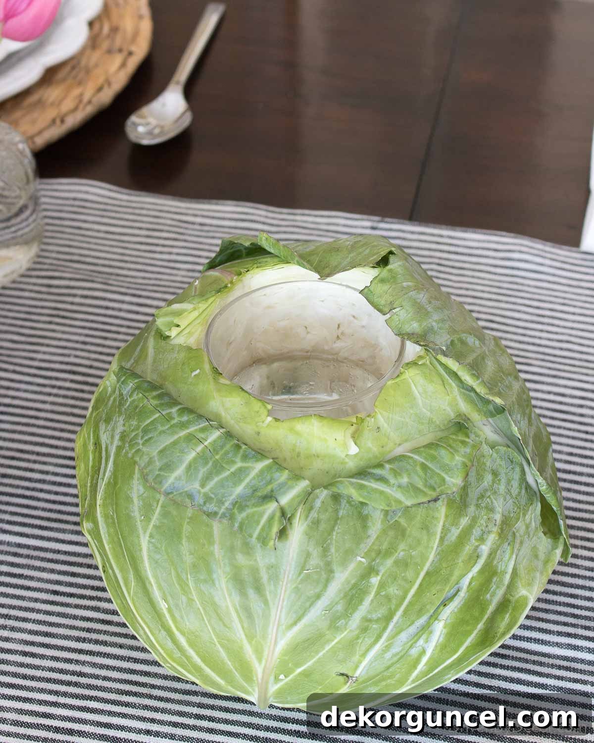 Detailed image of a hollowed-out cabbage, meticulously prepared to serve as a unique and rustic vase for a floral arrangement.