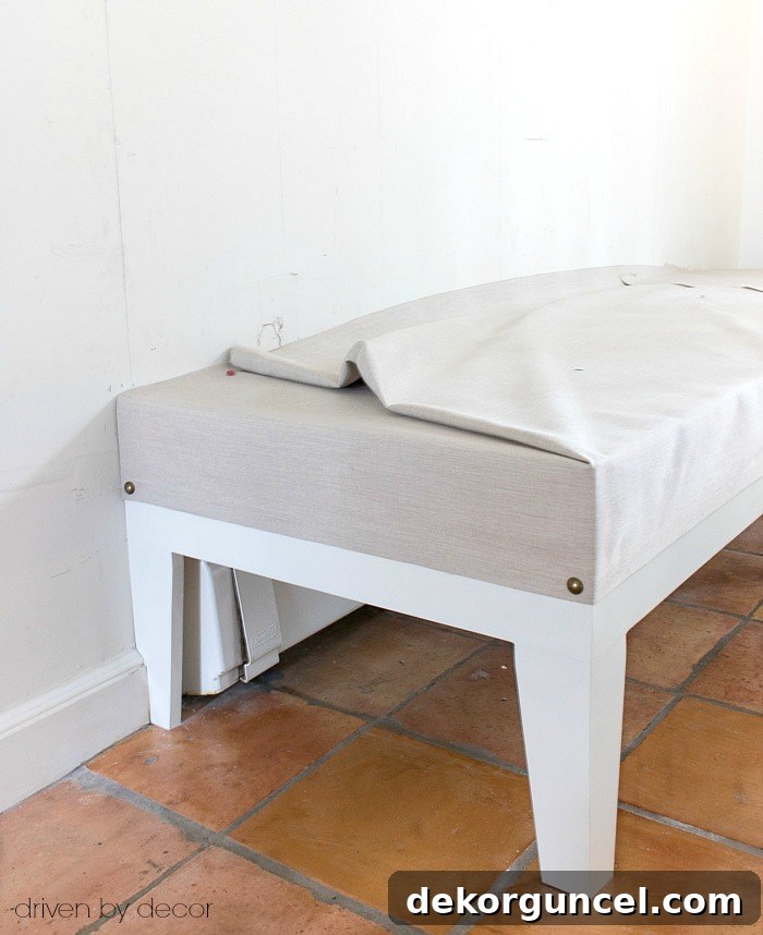 Build Your Own Banquette Seating 12 Attaching fabric and nailhead trim to a kitchen bench seat, starting with end anchors.