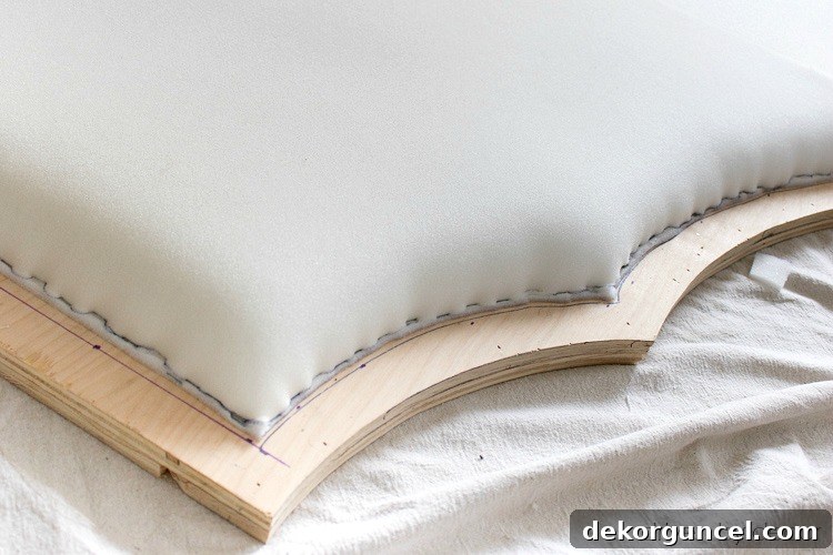 Build Your Own Banquette Seating 5 Stapling edges of foam onto plywood headboard for secure upholstery.