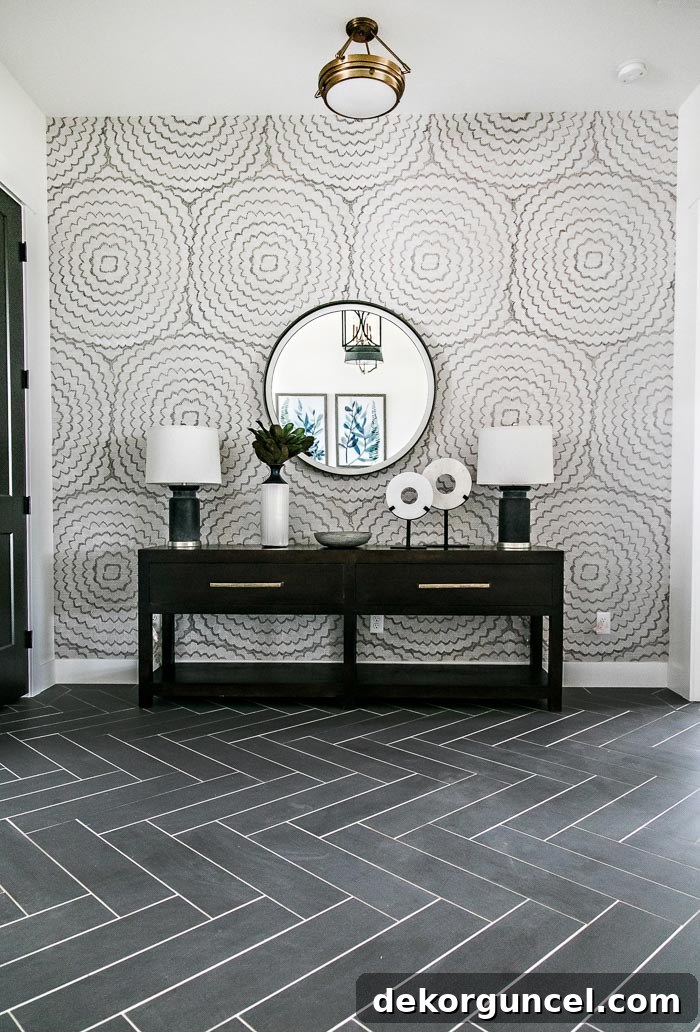 Stunning entry designed by Sita Montgomery Interiors with black herringbone floors and a long console with twin lamps and a round mirror.