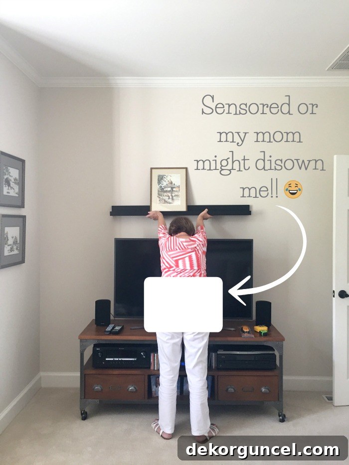 Above TV Shelf: Smart Storage, Seamless Style 4 A person holding a ledge shelf up to the wall above a TV, demonstrating the process of determining the ideal hanging height for a ledge shelf.