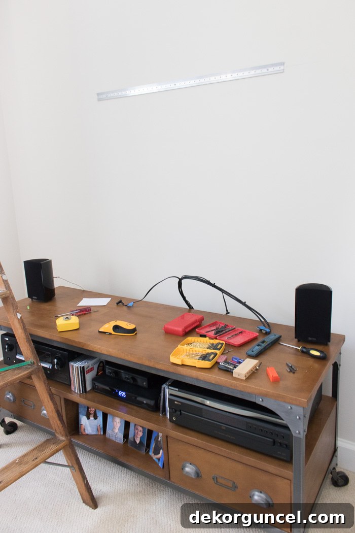 Above TV Shelf: Smart Storage, Seamless Style 5 Detailed image showing the process of hanging an art ledge shelf above a television and media console, highlighting the secure installation.