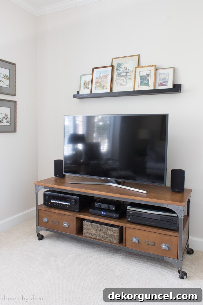 Above TV Shelf: Smart Storage, Seamless Style 7 The 'after' picture of the TV wall, now beautifully decorated with framed art prints arranged on a black ledge shelf above the flat screen TV.