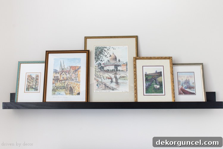 Above TV Shelf: Smart Storage, Seamless Style 9 Close-up of framed art prints arranged on a ledge shelf, showcasing how overlapping them creates a more cohesive and visually interesting, collected look.