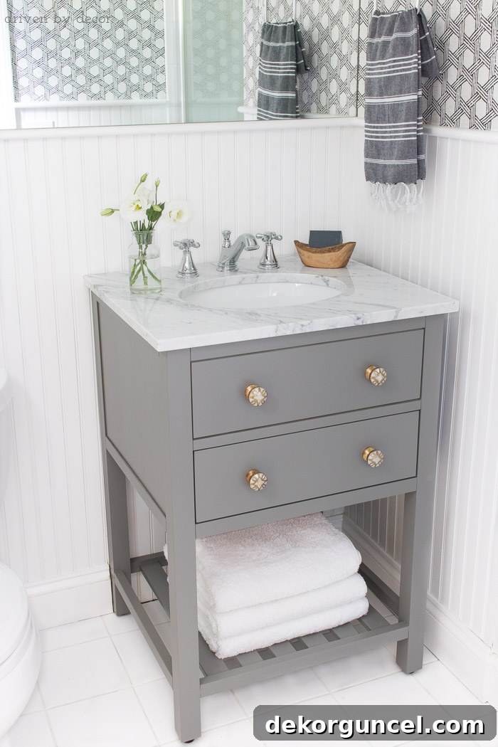 Small space single sink gray vanity with white marble top and classic Delta Cassidy bathroom faucet - links to everything in post!