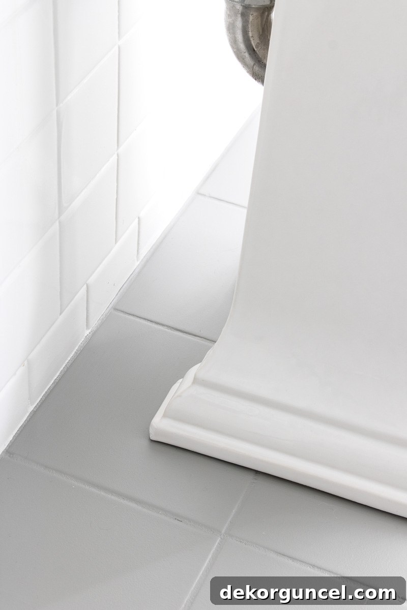 How to Paint a Tile Floor: Essential Tools and Proven Tips 5 After photo showing the cleanly painted ceramic tile floor behind a modern pedestal sink, demonstrating complete stain coverage.