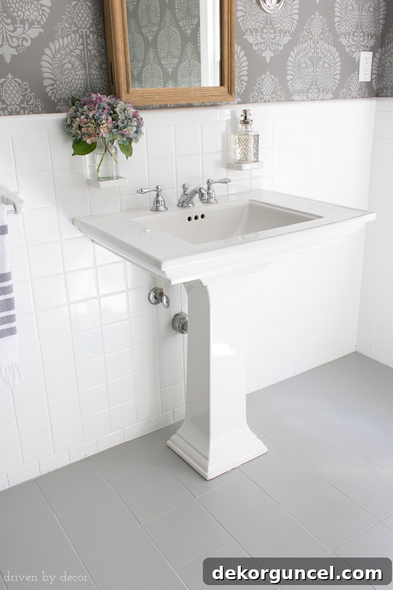 How to Paint a Tile Floor: Essential Tools and Proven Tips 6 Elegant powder room featuring a sleek pedestal sink set against newly painted gray ceramic tile floors, enhancing the room's modern aesthetic.