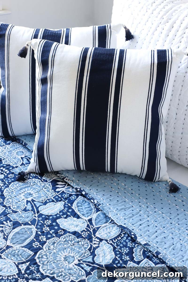 A delightful combination of the beautiful blue and white Vera Bradley floral quilt paired with complementary navy stripe tasseled pillows, adding charm and texture.