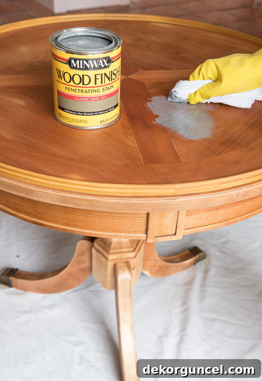 How to Refinish an End Table From Beat Up to Beautiful 8 Minwax Classic Gray stain being applied to a refinished red oak table