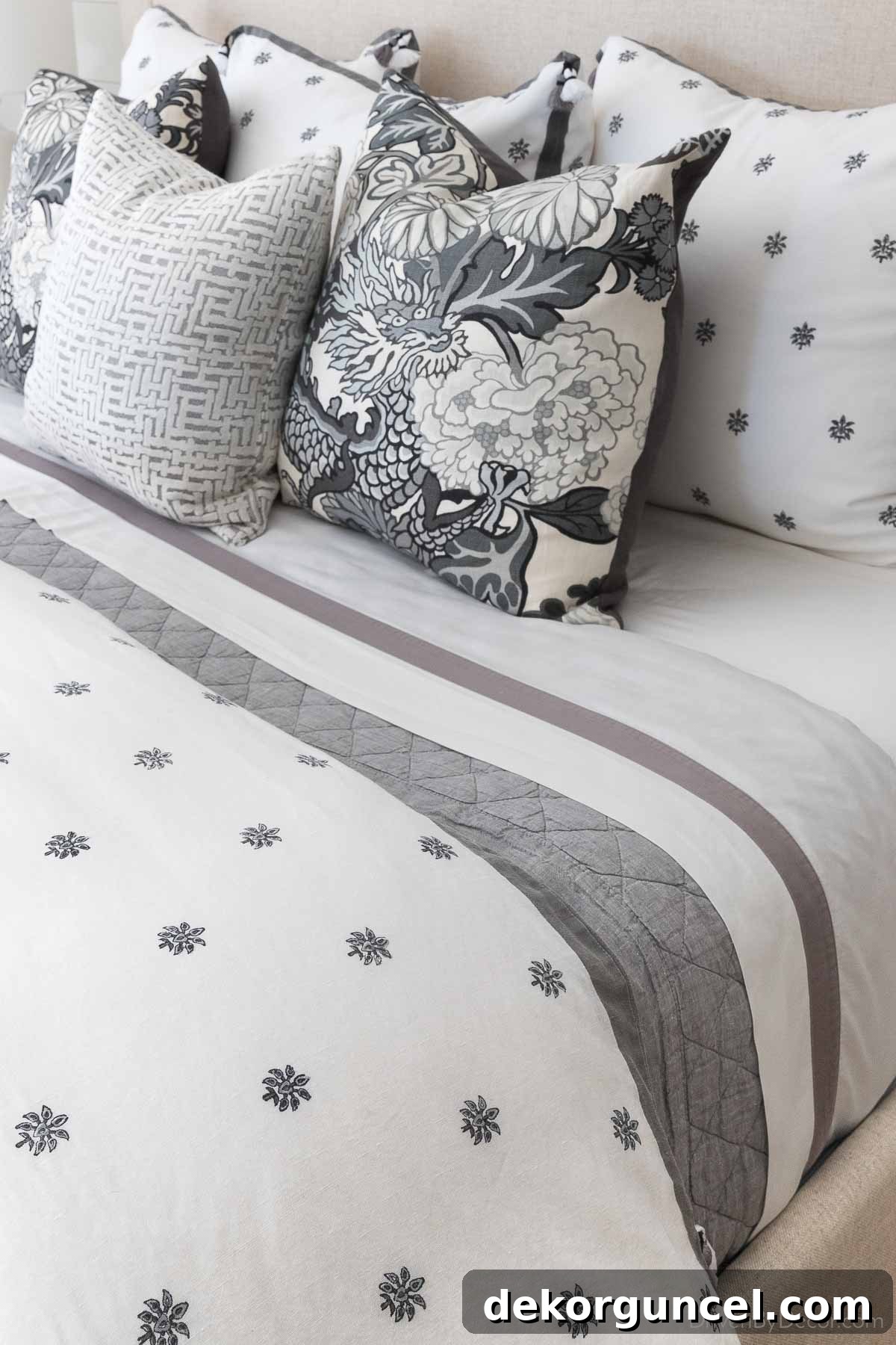 A beautifully made guest bed with a gray Belgian Flax Linen Diamond quilt, crisp white sheets, and a fluffy duvet, showcasing elegant layered bedding.