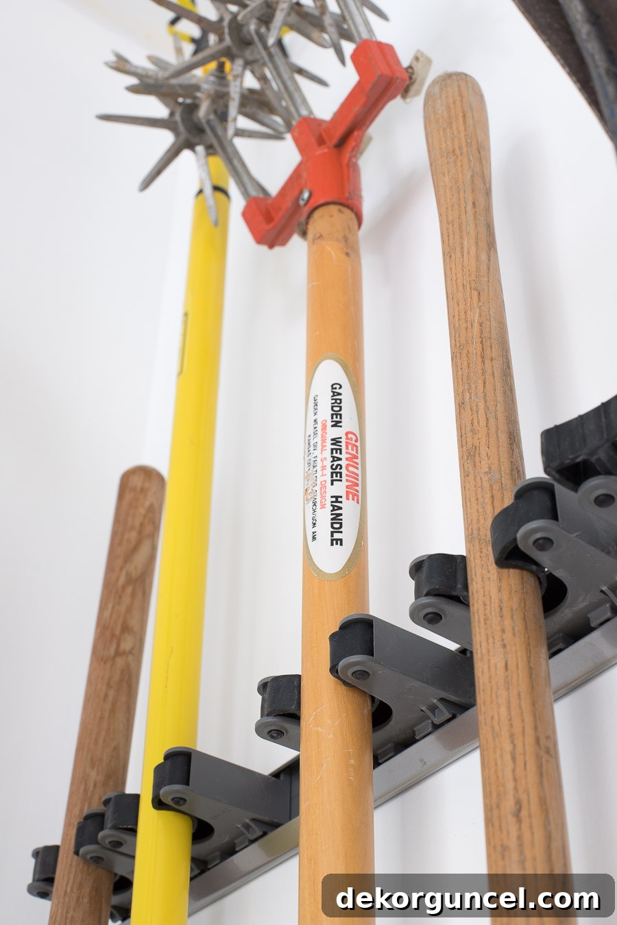 Close-up of organized long-handled tools hanging on Elfa individual tool holders.