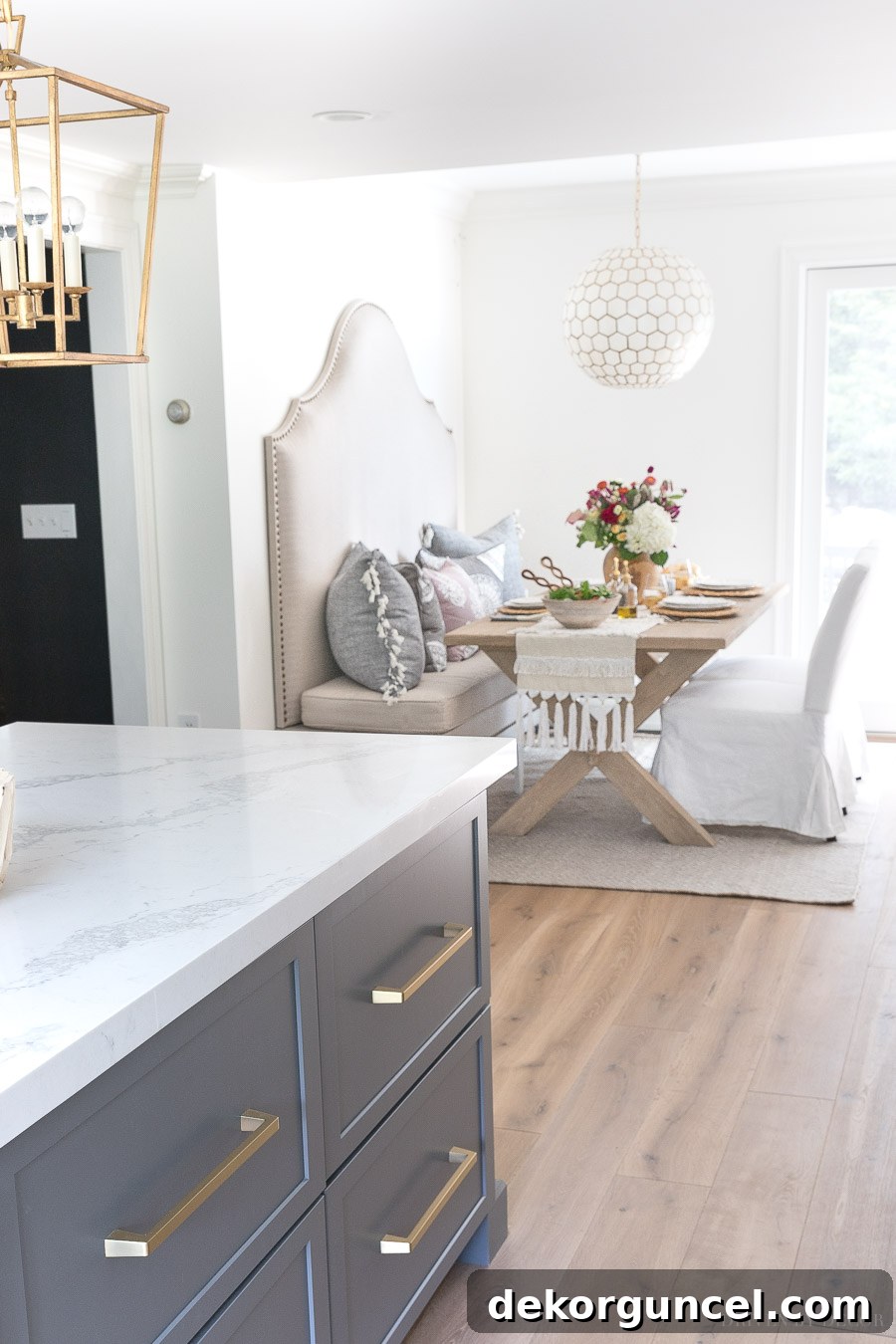 Our newly remodeled kitchen eat-in area, showcasing a beautifully designed breakfast nook with a banquette, wood table, slipcovered dining chairs, and an elegant capiz pendant light.