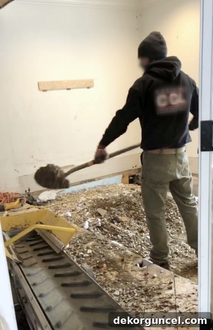 Excavation in progress: A worker jackhammering out the concrete floor of the breakfast nook to prepare for new, level flooring, showcasing the initial demolition phase of the kitchen remodel.