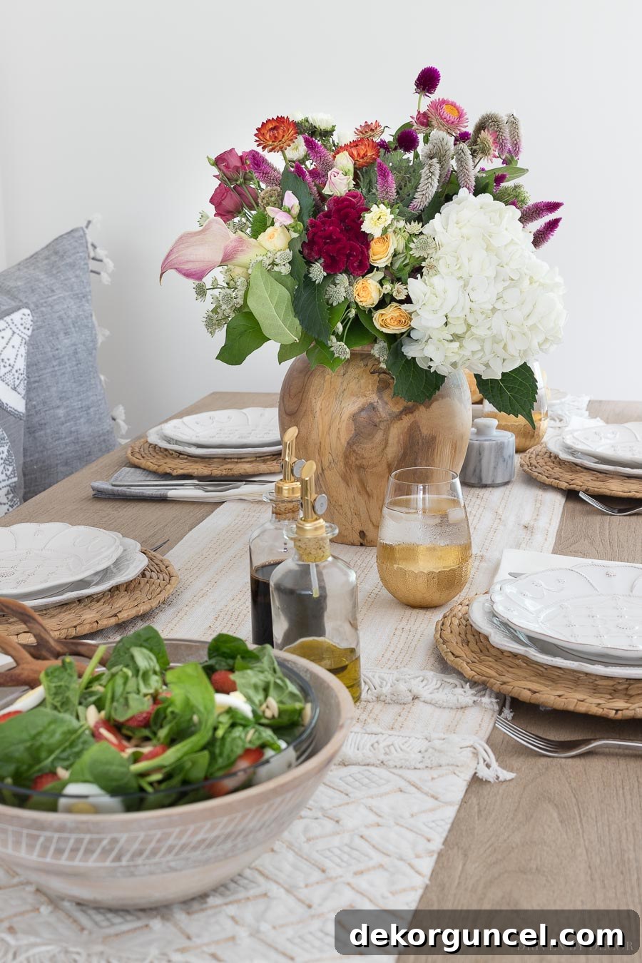 A naturally textured tablescape, featuring a beautiful wood vase with fresh flowers and a neutral table runner, creating a warm and inviting atmosphere. All sources, including the pretty vase, are linked in the post.