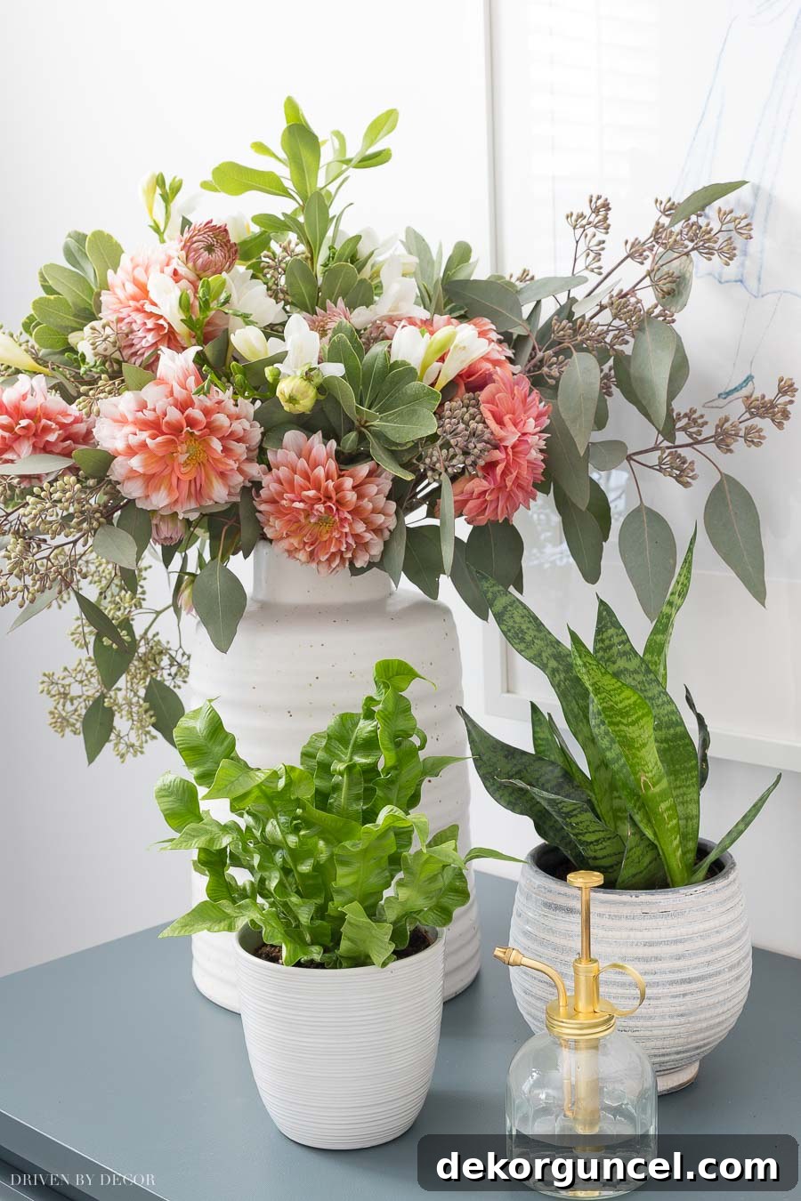 A collection of lush green plants in gorgeous textured white planters and vases adorning a dresser, adding natural beauty and life to a boho chic bedroom.