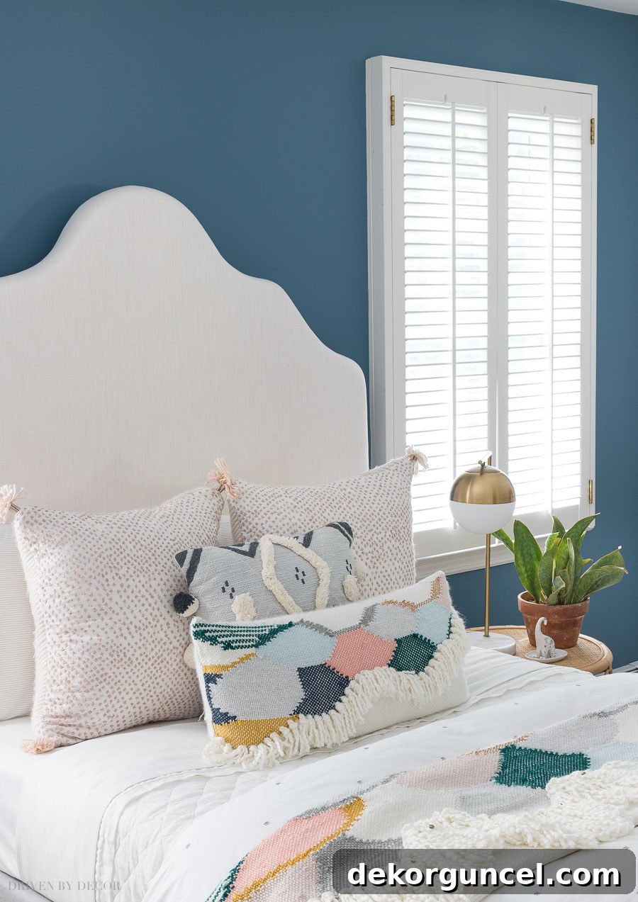 A luxurious bedscape in a boho chic bedroom, featuring a stunning combination of blush and blue pillows, a colorful throw, and a cozy white quilt.