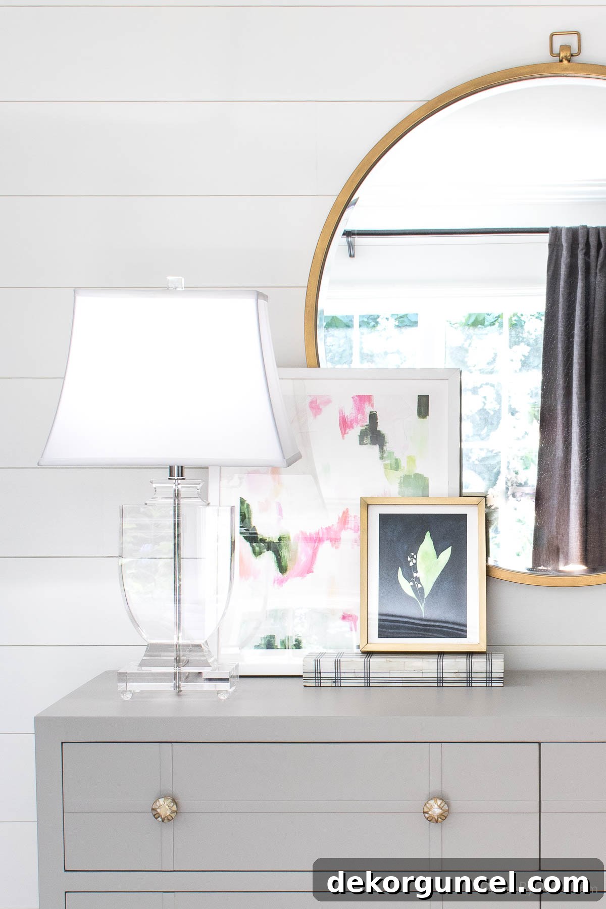 Behind the Illumination: My Home's Fixture Selections 20 An elegant acrylic urn-shaped table lamp positioned on a gray dresser, showcasing its timeless design and versatility.