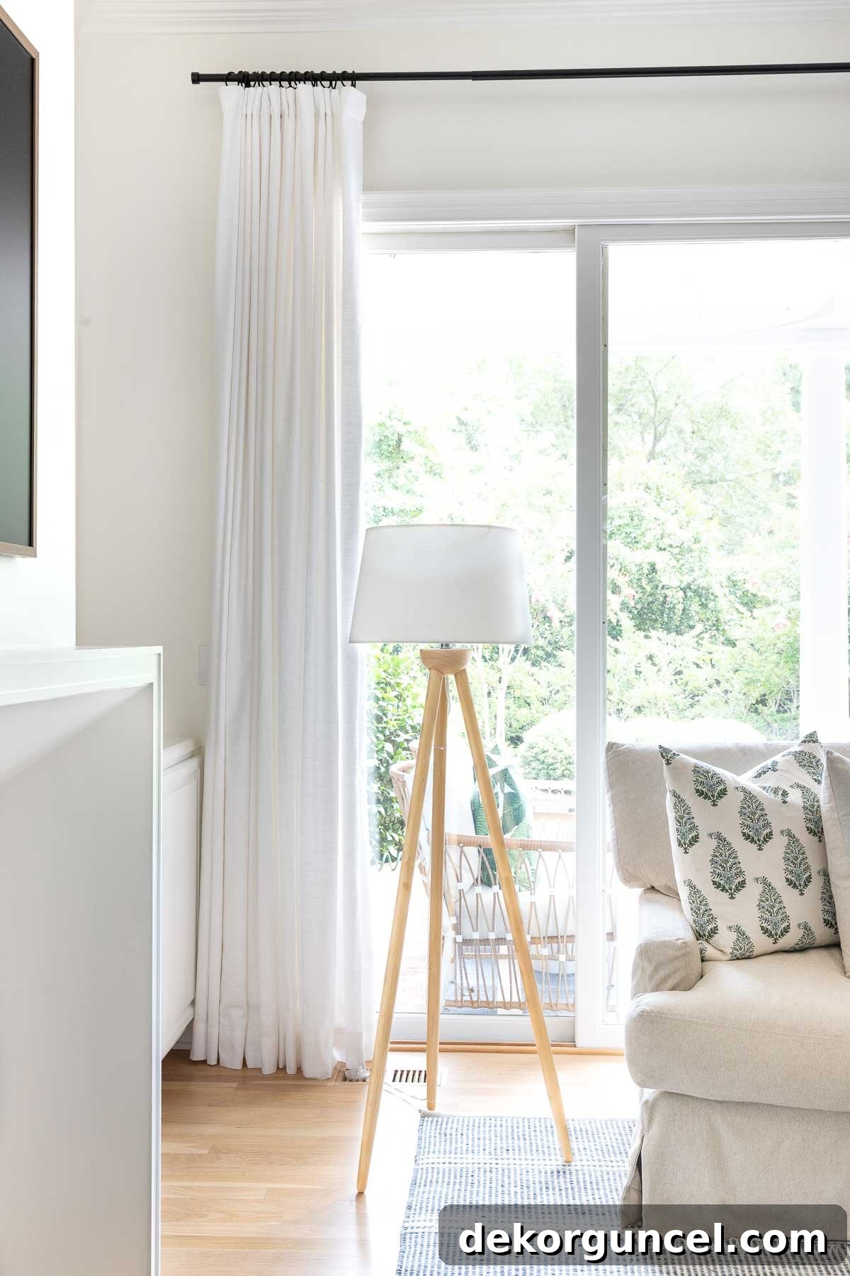 Behind the Illumination: My Home's Fixture Selections 31 A sturdy wood tripod floor lamp positioned next to a comfortable sectional sofa in a family room, providing warm ambient light.