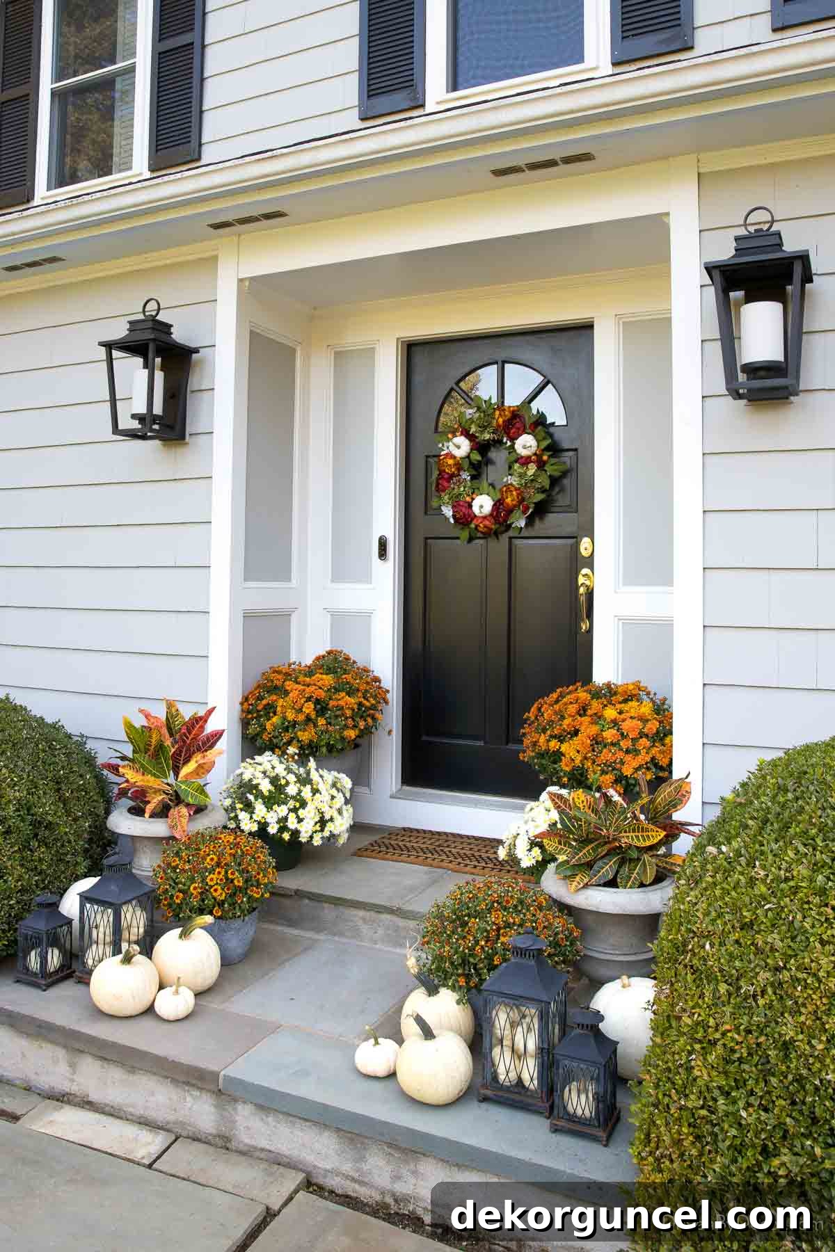 Behind the Illumination: My Home's Fixture Selections 39 A welcoming fall front porch adorned with white pumpkins, mums, and crotons, illuminated by large, stylish wall lanterns.