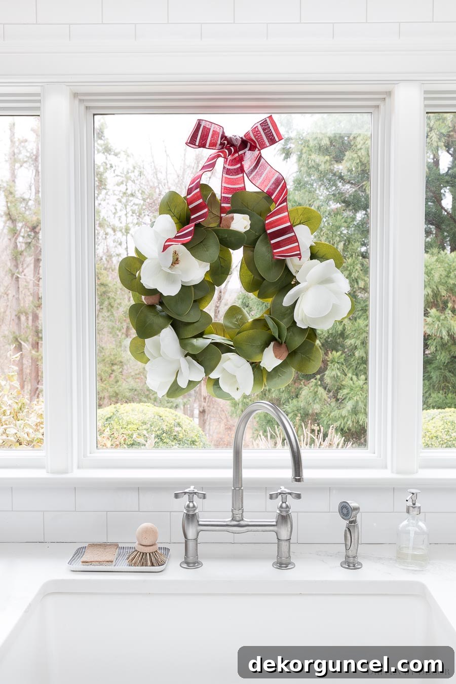 A beautiful magnolia wreath adorned with a vibrant red watercolor ribbon, creating a simple yet striking holiday accent.