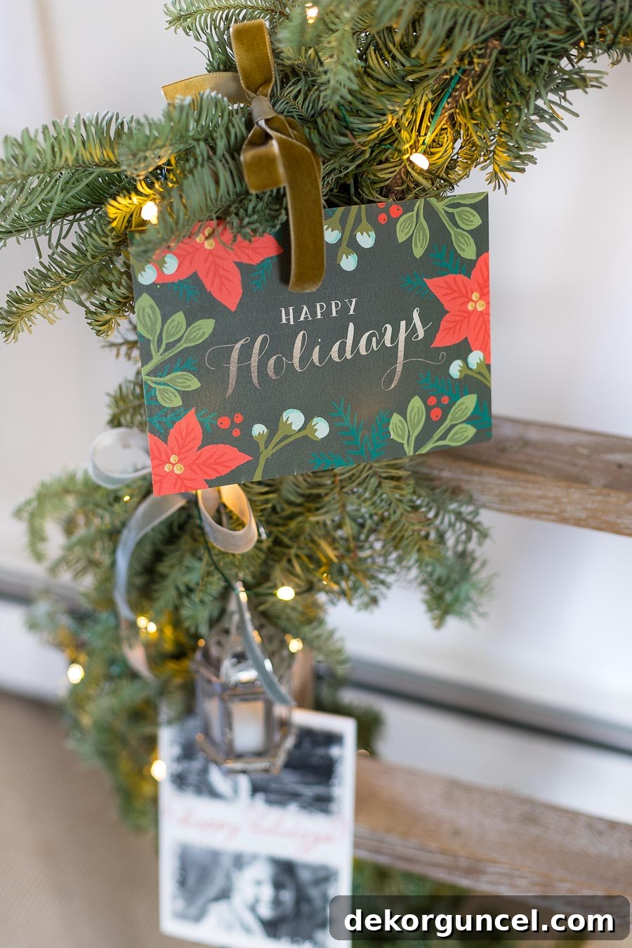 Charming Christmas card display featuring cards tied onto a ladder adorned with garland and ribbon, creating a unique holiday decor element